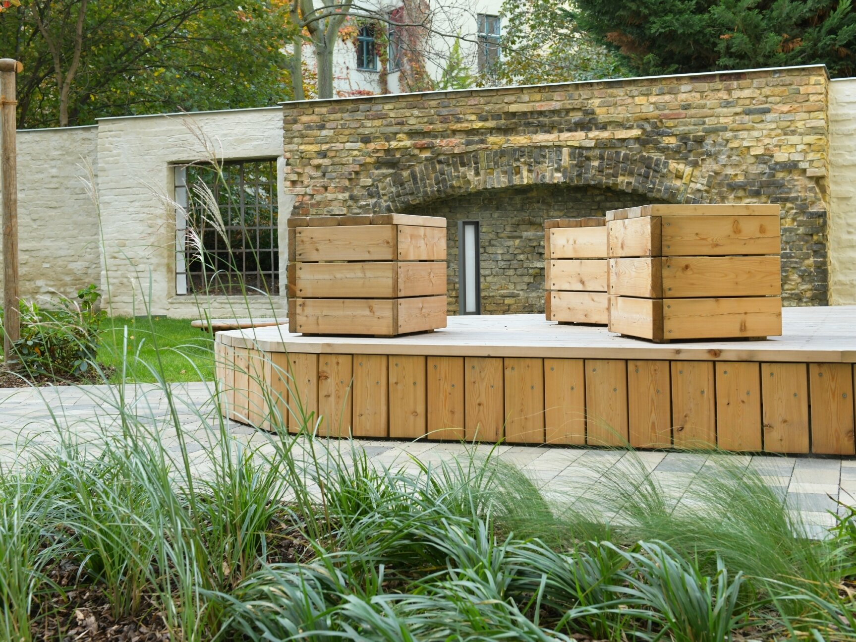 Außenansicht degewo-Neubau Klara-Franke-Straße 1 bis 7: Hofseite mit Sitzgelegenheiten auf Erhöhung und Beet im Vordergrund.
