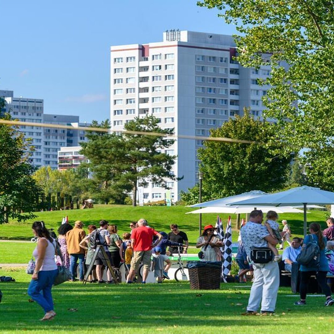 Mieter auf dem degewo-Mieterfest in den Gärten der Welt. Im Hintergrund sind Plattenbauten zu sehen. 