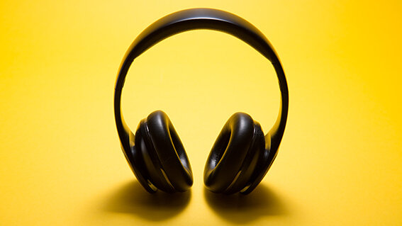 Schwarzer Kopfhörer vor einem gelben Hintergrund. 