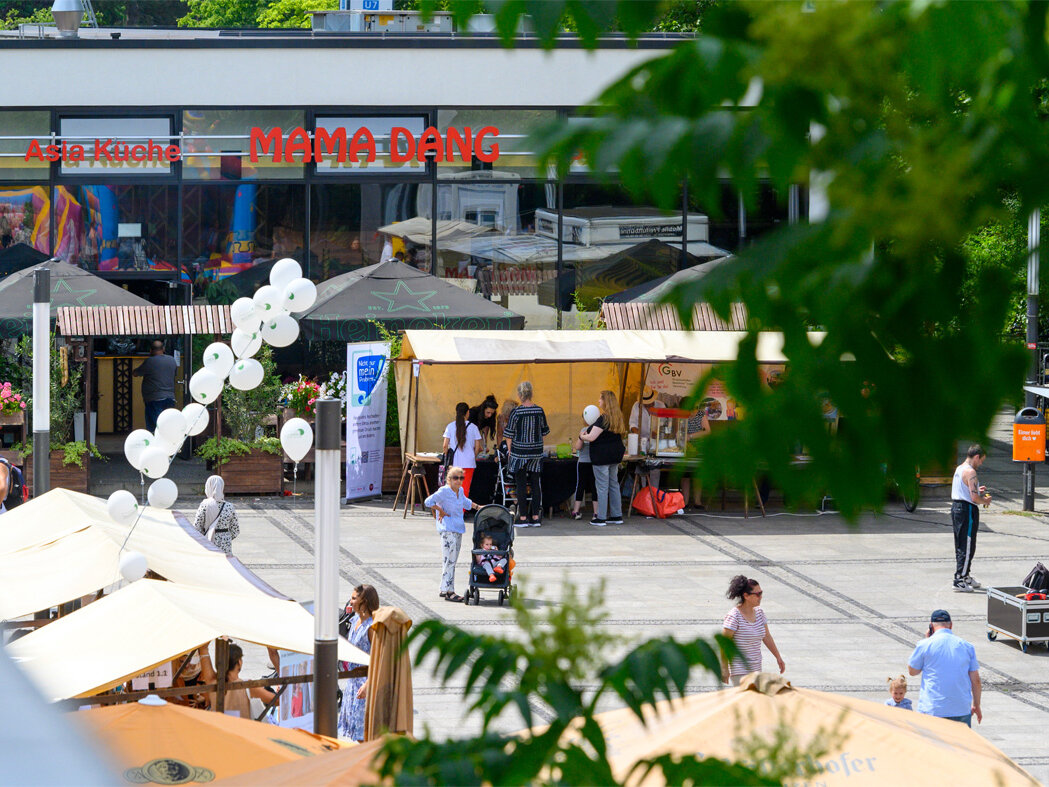 Blick von oben auf den Platz, weiße Luftballons wehen.