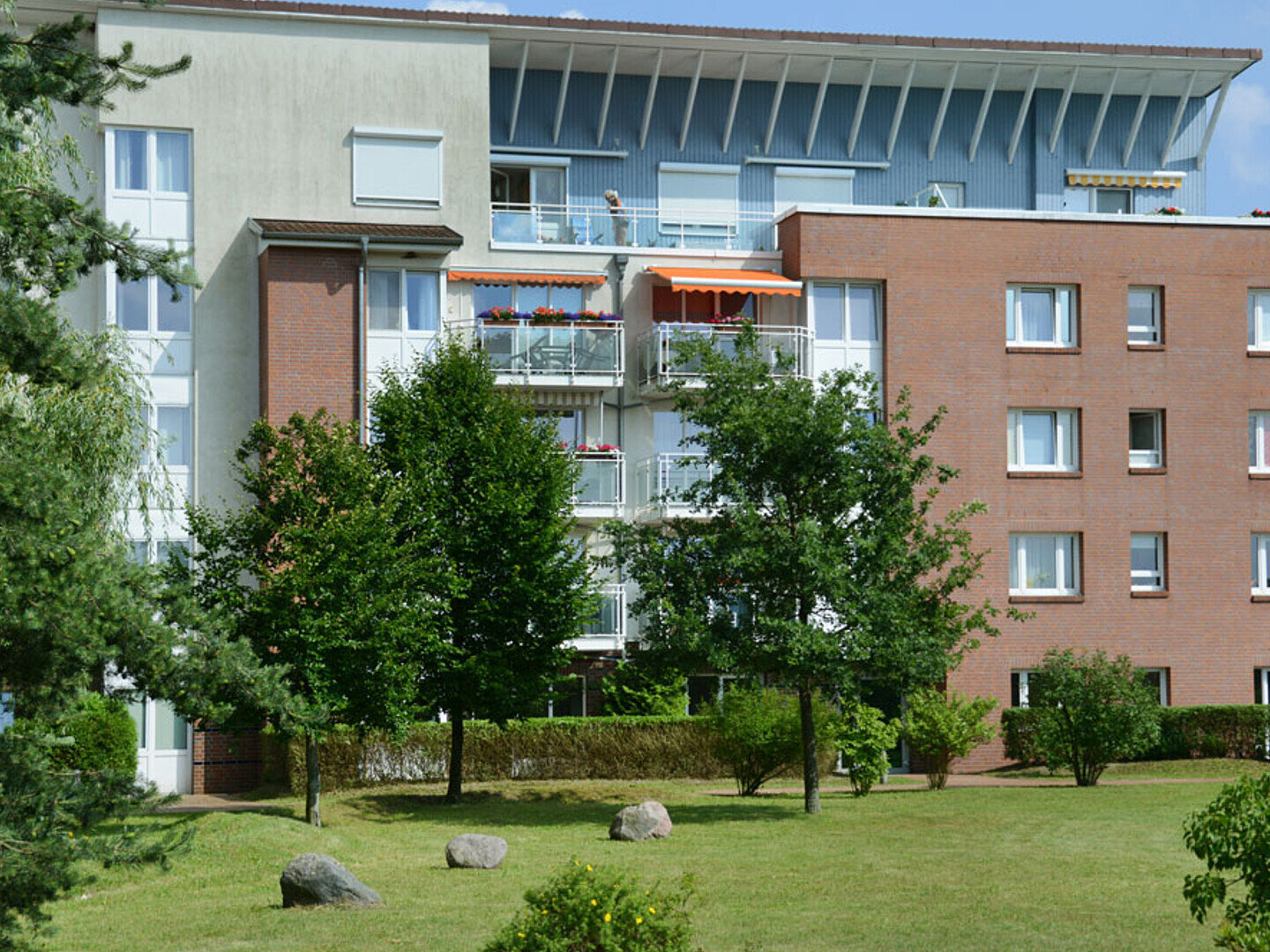Blick auf einen Wohnkomplex mit Klinkerfassade, oben eine Dachterrasse