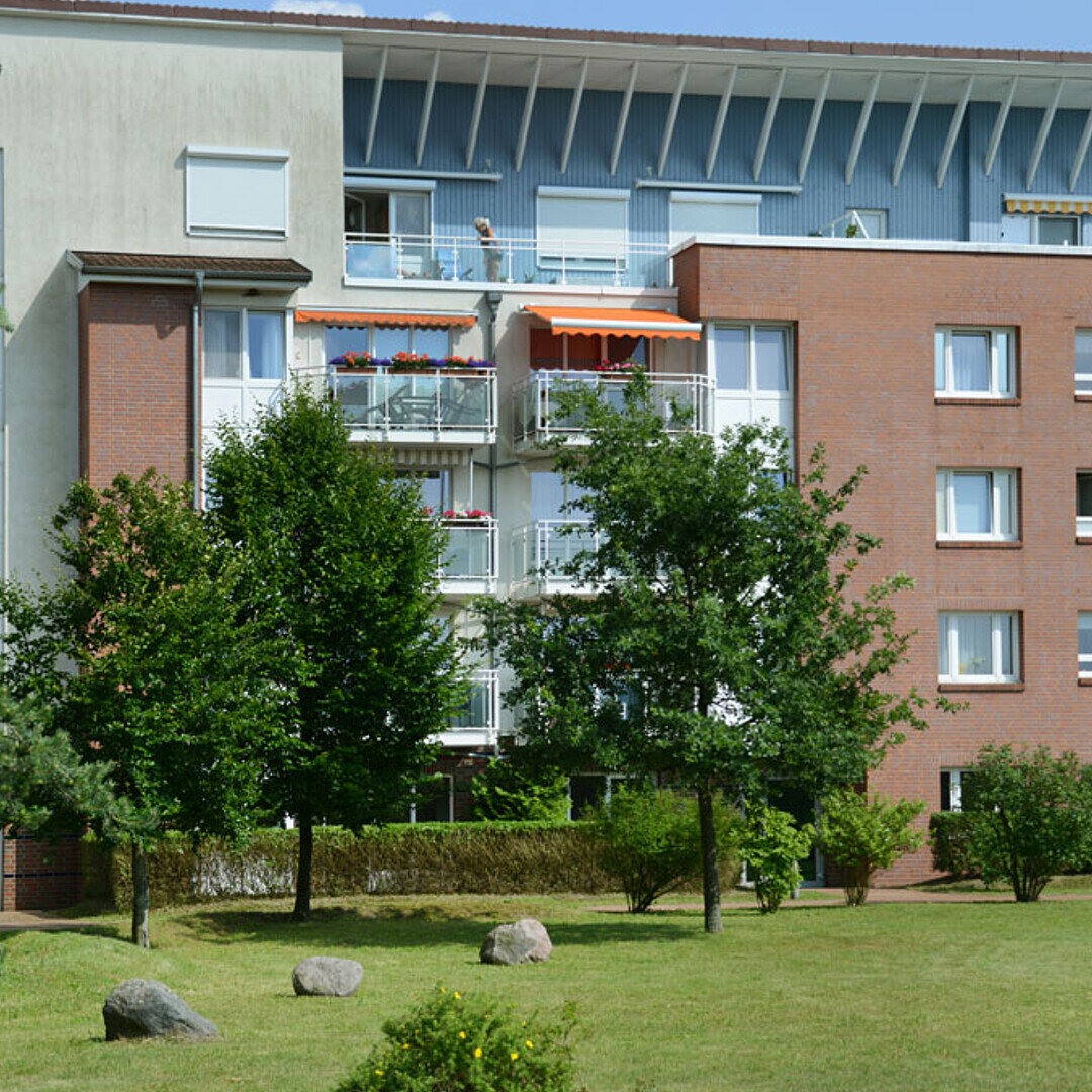 Blick auf einen Wohnkomplex mit Klinkerfassade, oben eine Dachterrasse