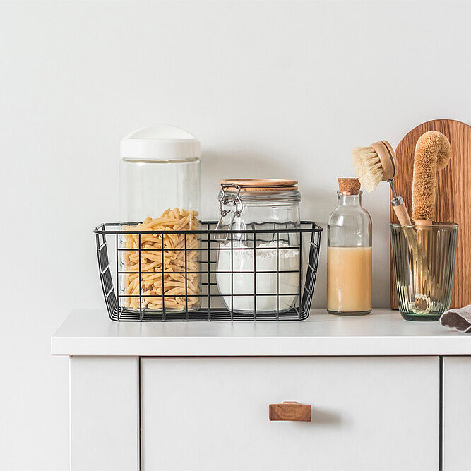 Ein Küchenunterschrank mit einer Flasche Saft und Gläsern mit Deckeln und Cornflakes.