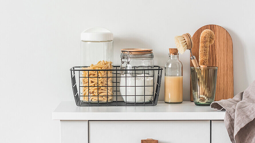 Ein Küchenunterschrank mit einer Flasche Saft und Gläsern mit Deckeln und Cornflakes.