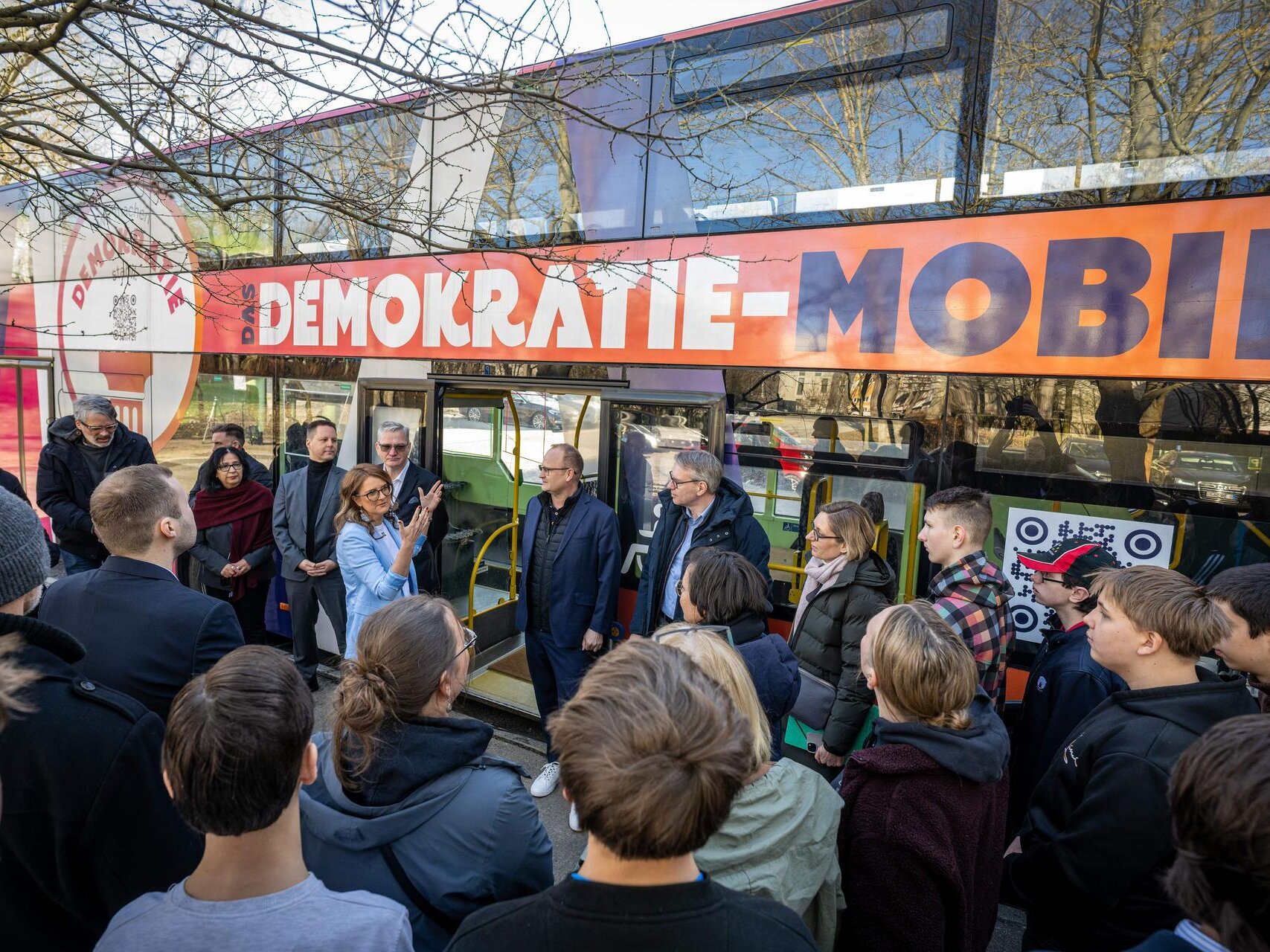 Eine Menschengruppe steht vor dem Demokratie-Mobil.