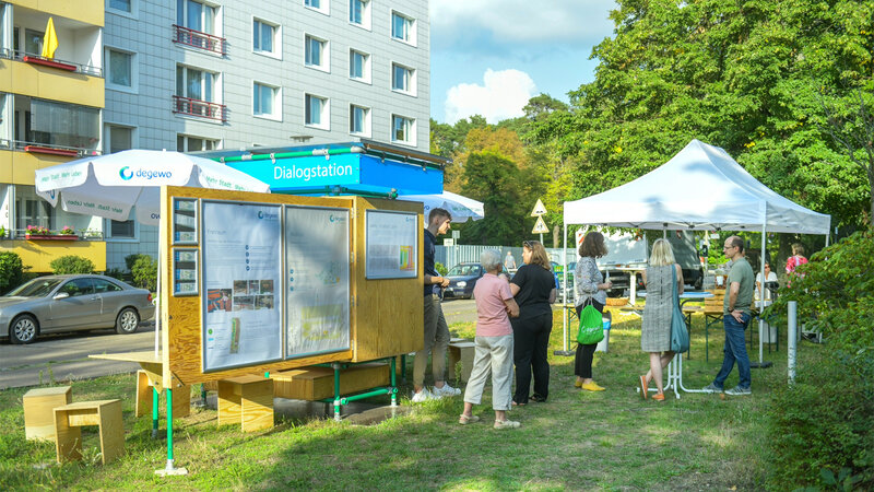 degewo-Dialogstation mit Informationsplakaten zum Neubauvorhaben im Wohngebiet Allende I: Anwohnende kommen unter Pavillons ins Gespräch und informieren sich über Freiraum, Mobilität und Planung.
