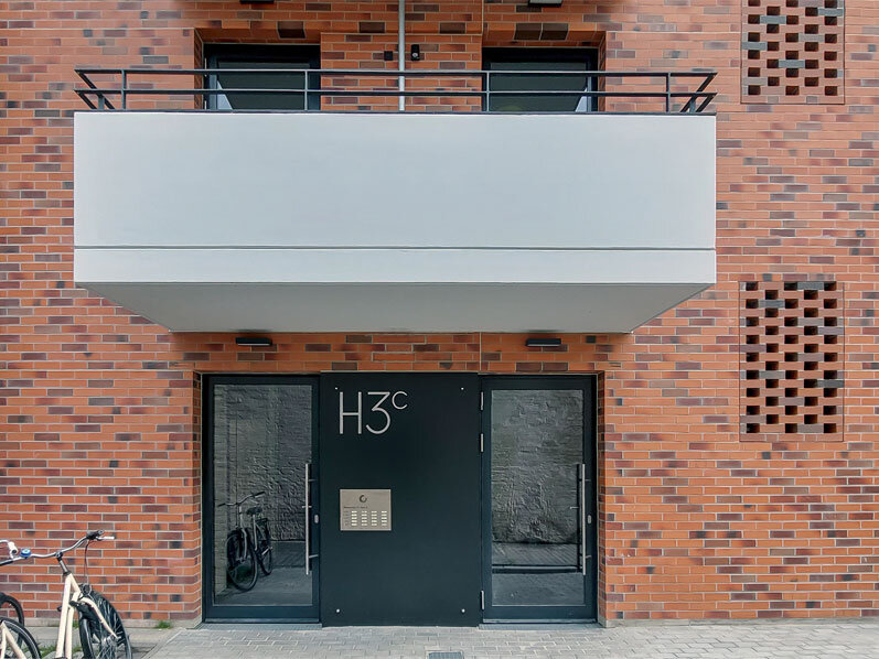 Außenansicht degewo-Neubau Wiesenstraße 55: Eingangsbereich Haus 3c mit Fahrradständern links.