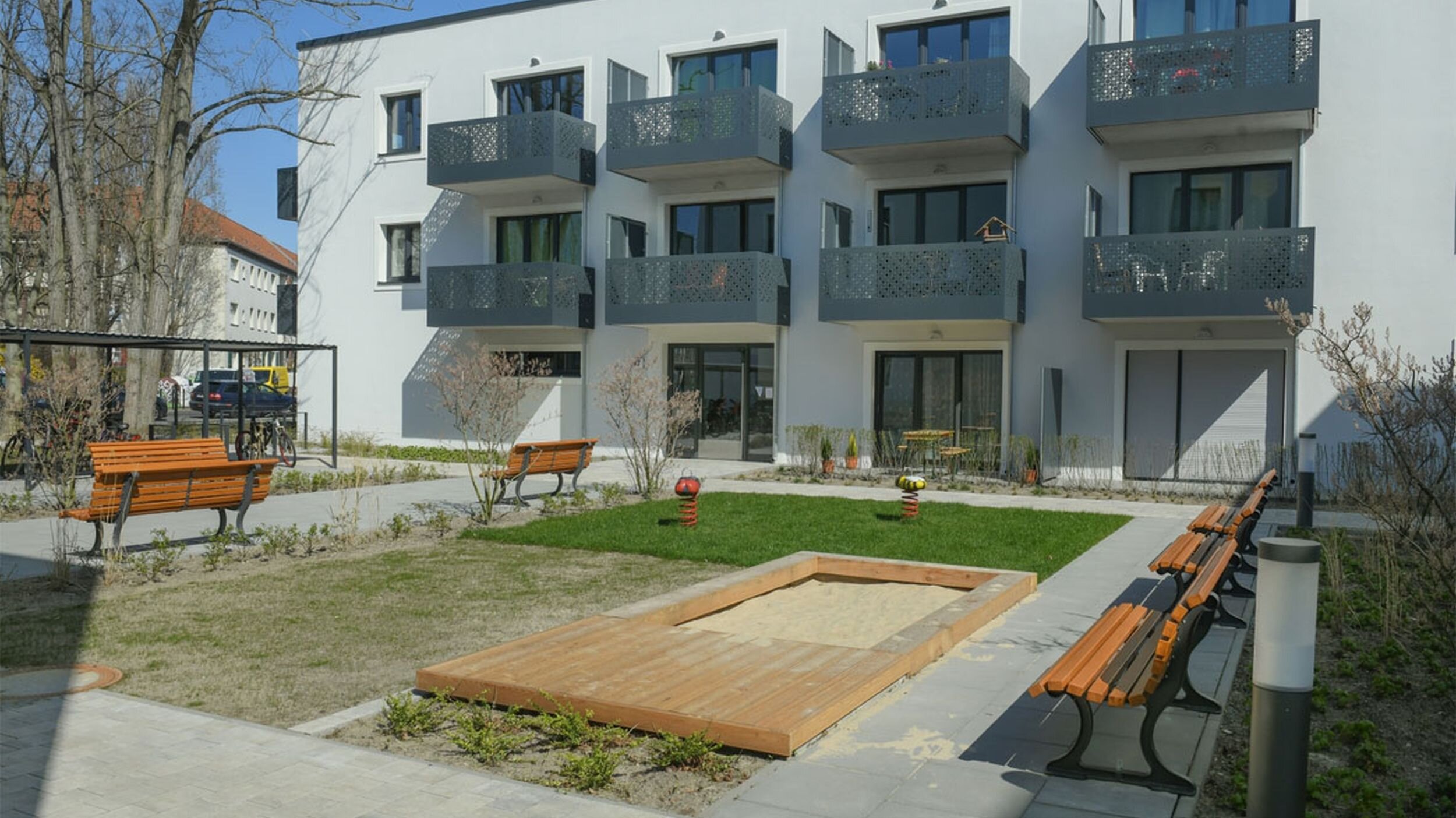 Außenansicht degewo-Neubau Rudower Straße 47 bis 51: Hofseite mit Spielplatz und Sitzbänken.