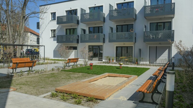 Außenansicht degewo-Neubau Rudower Straße 47 bis 51: Hofseite mit Spielplatz und Sitzbänken.