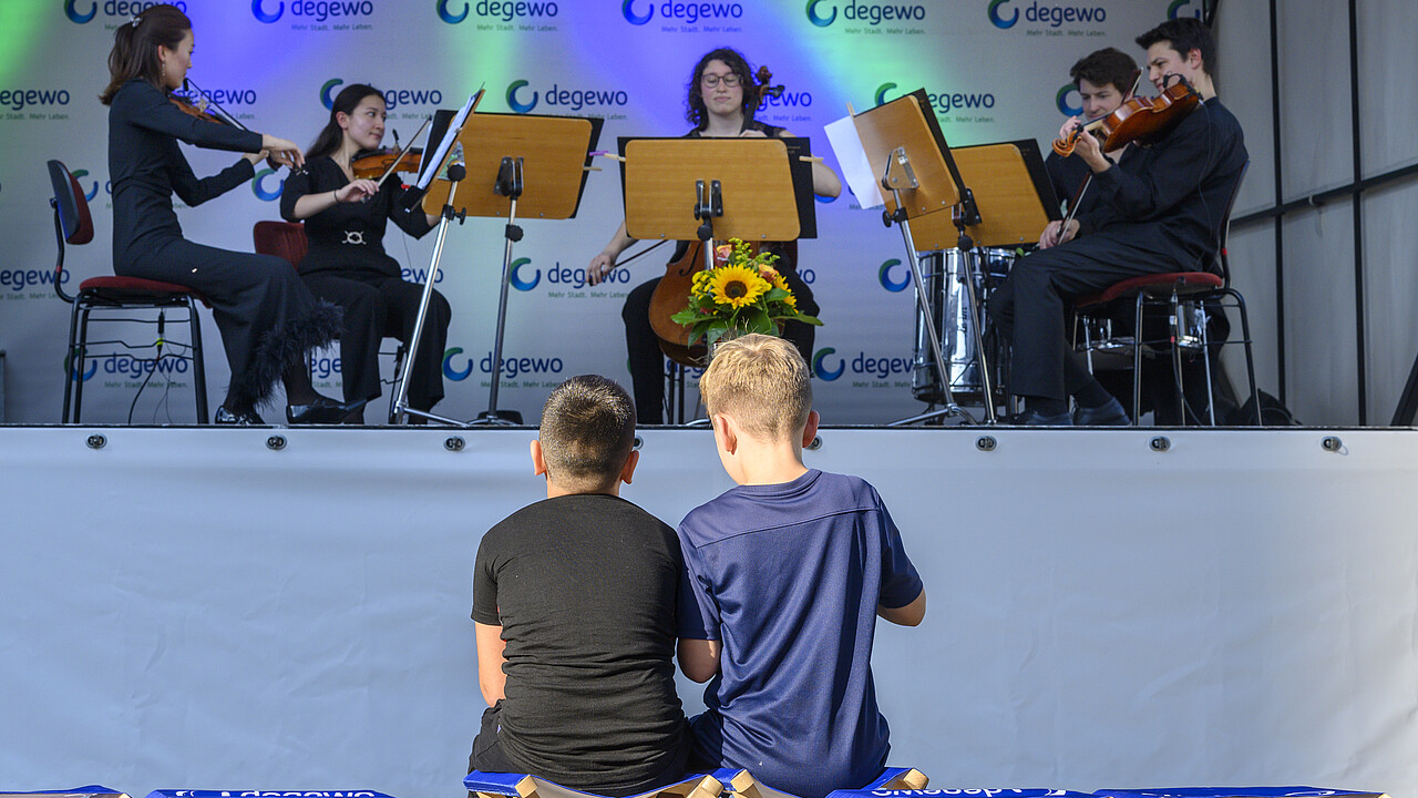 Kinder sitzen vor Bühne mit Musikern