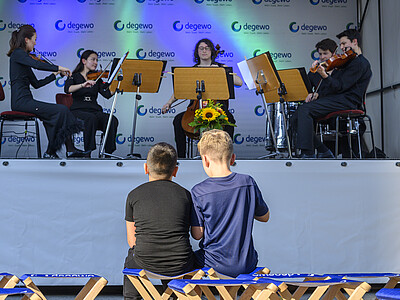 Kinder sitzen vor Bühne mit Musikern
