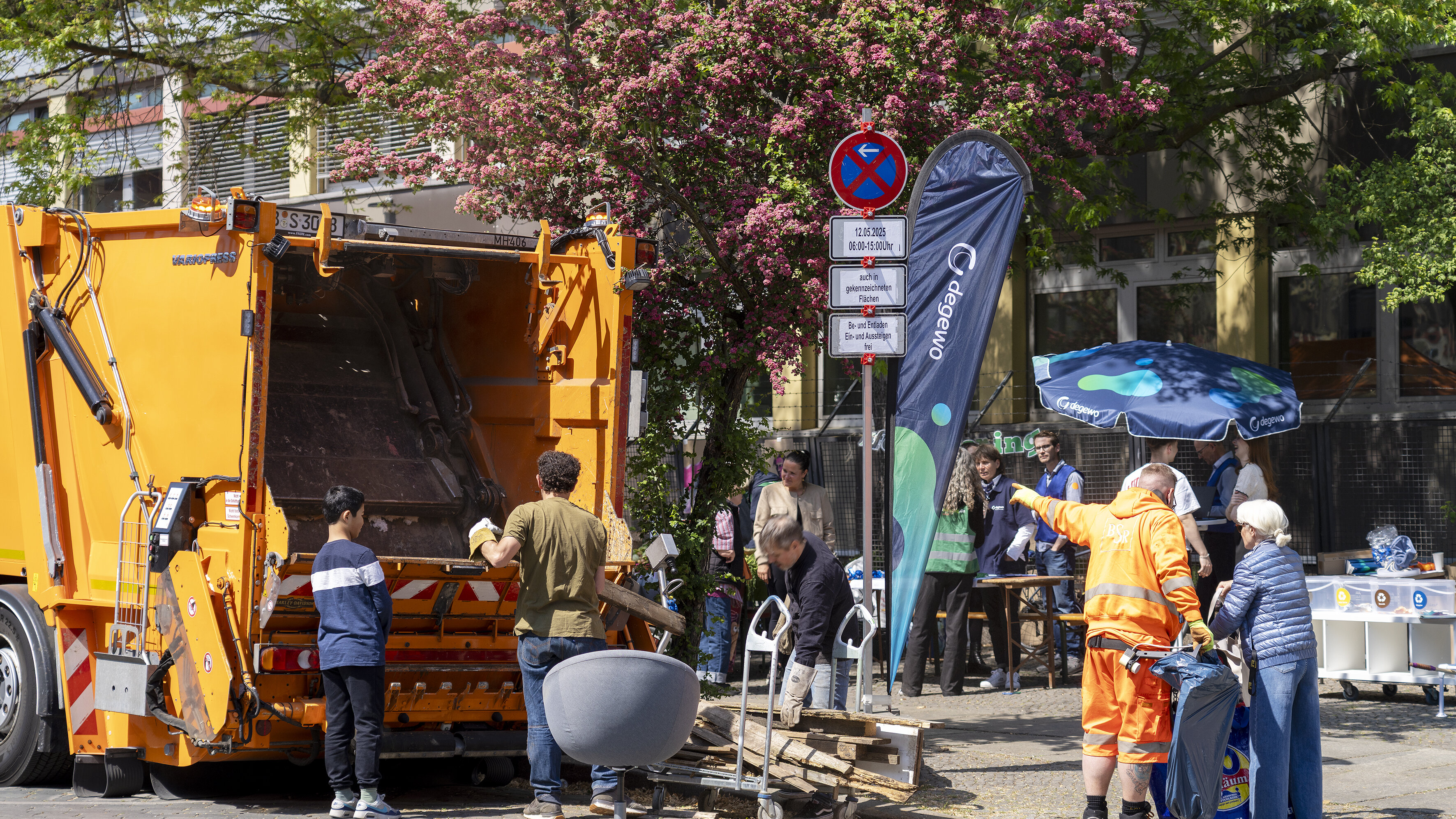 Menschen entsorgen Sperrmüll gemeinsam an einem Müllfahrzeug.