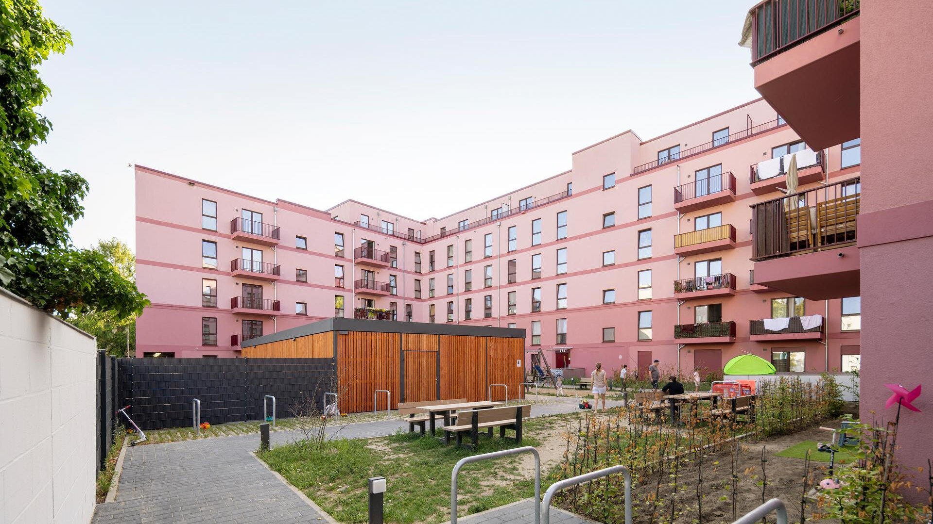 Neubau Bismarckstraße in Spandau, Innenhofansicht des Wohngebäudes mit Balkonen, Fahrradstellplätzen, Pkw-Stellflächen und begrünten Freiflächen.