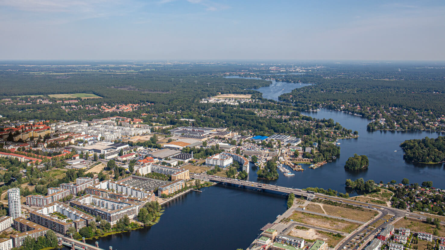 Ein Luftbild zeigt Wohnquartiere, Industrieflächen, Brücken und Wasserlandschaften im Bezirk Spandau aus der Vogelperspektive. Zu den gezeigten Wohnquartieren gehören auch die Pepitahöfe.