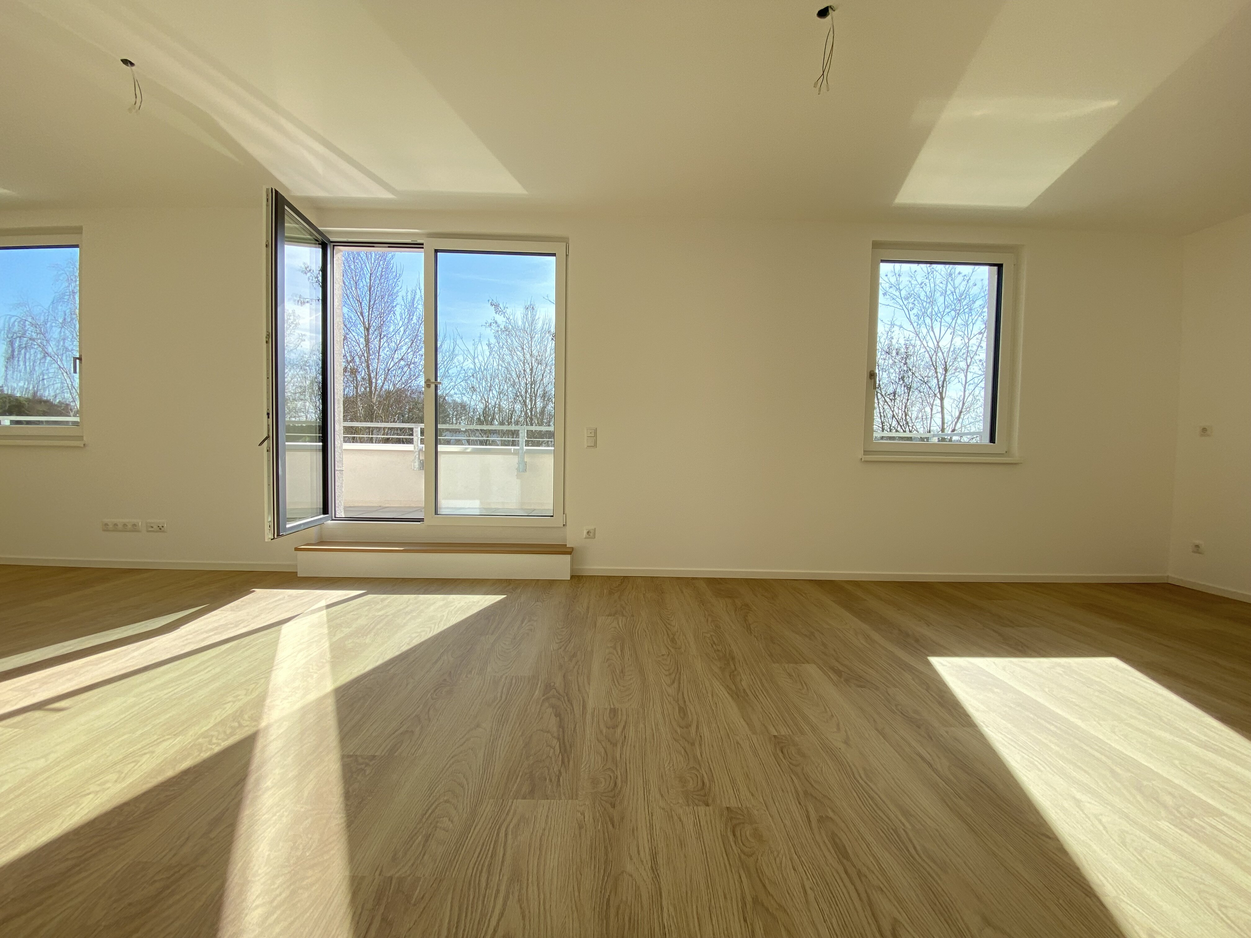 Innenansicht degewo-Neubau Fürstenwalder Allee 324/326: leeres Zimmer mit geöffneter Balkontür.