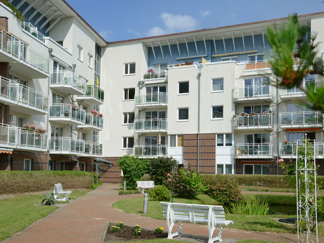 Innenhof eines zweiseitigen Hauses mit Bäumen und Bänken