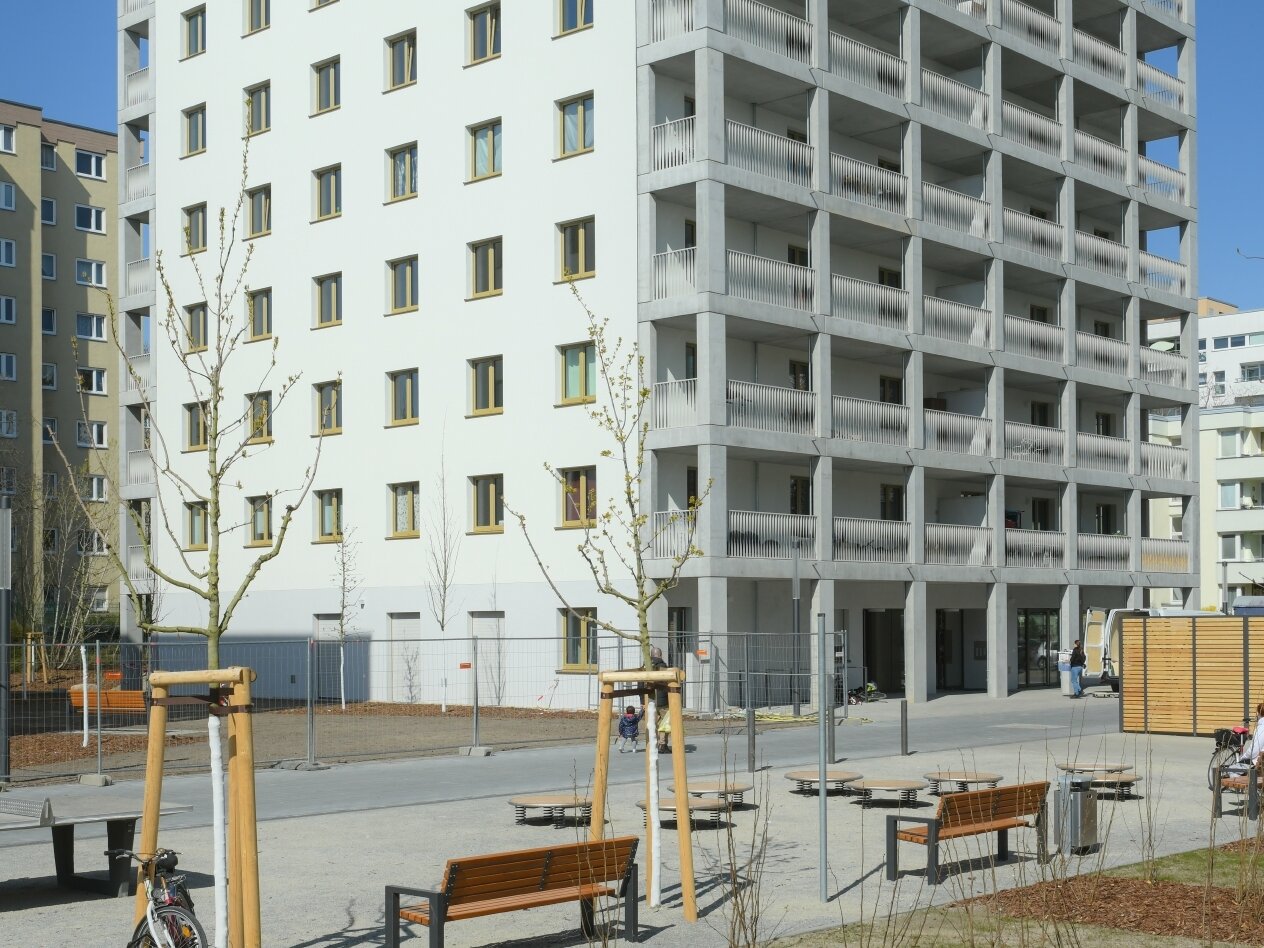 Außenansicht degewo-Neubau Theodor-Loos-Weg 31 bis 35 mit Grünflächen und Geländer rechts im Vordergrund.