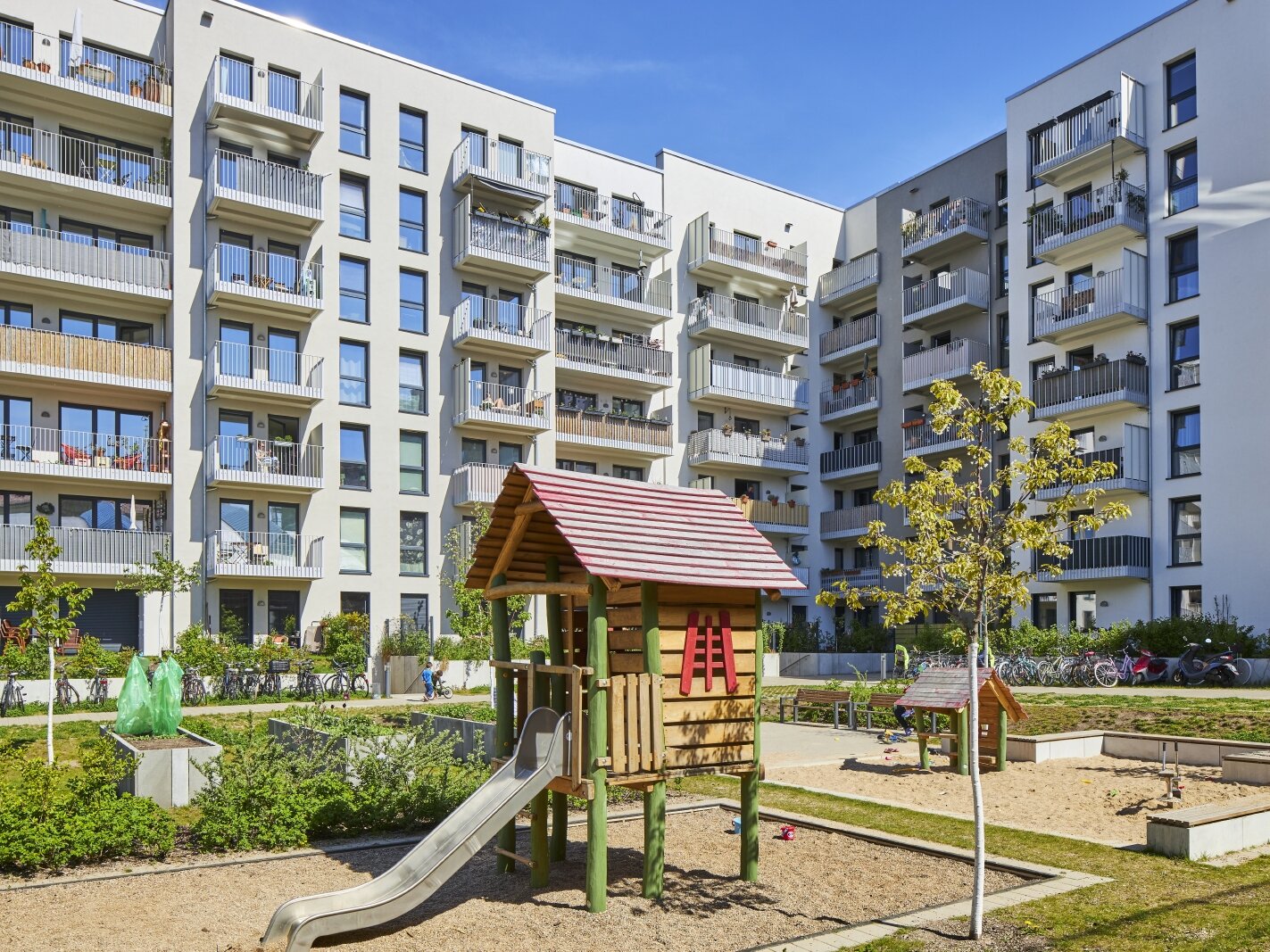 Außenansicht degewo-Neubau Usedomer Straße 25, 26 und 27: Hofseite mit Spielplatz im Vordergrund.