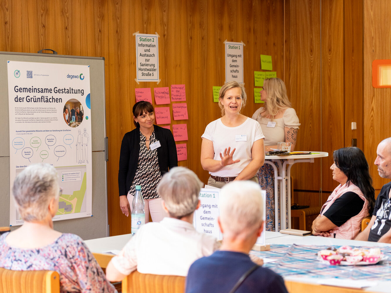 Mitarbeitende von degewo moderieren eine Gesprächsrunde zur Sanierung. Im Hintergrund stehen Infotafeln und Pinnwände mit Themen und Notizen.