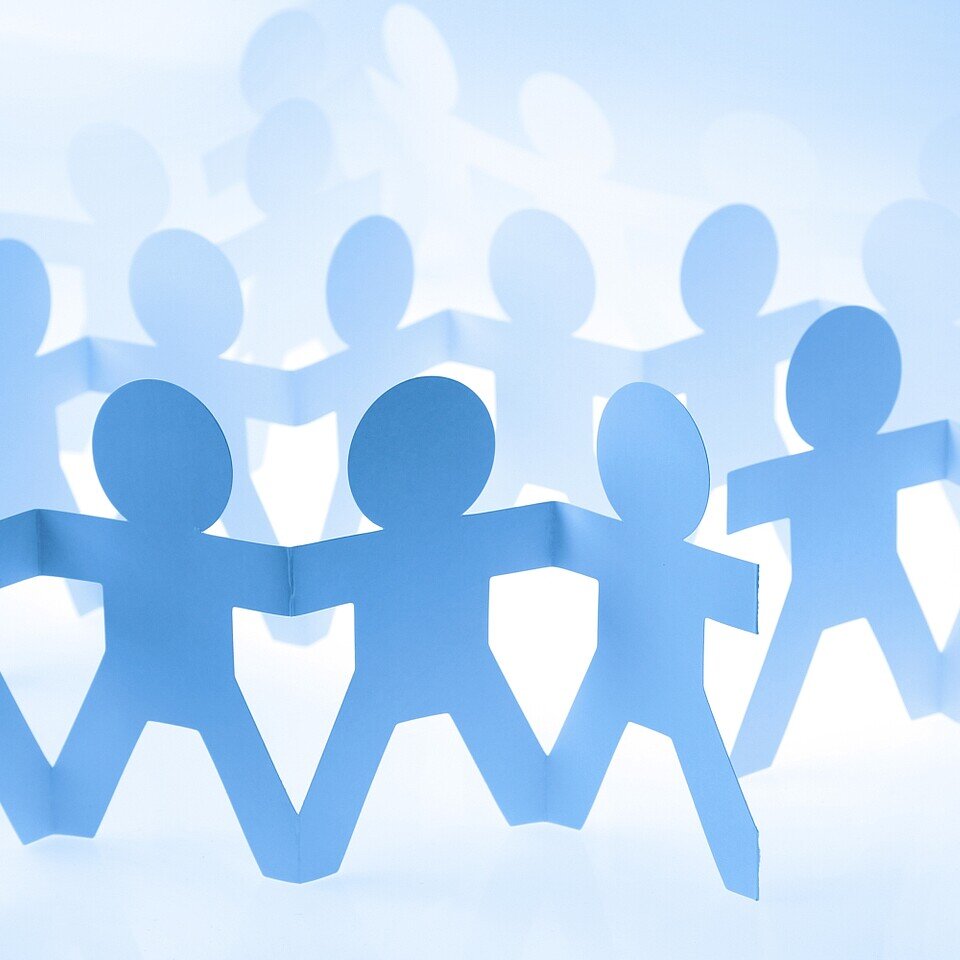 Illustration einer Gruppe Menschen, aus Papier gebastelt, die sich alle an den Händen halten. 