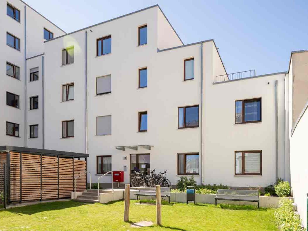 Außenansicht degewo-Neubau Glasower Straße 3 A mit Grünfläche im Vordergrund.