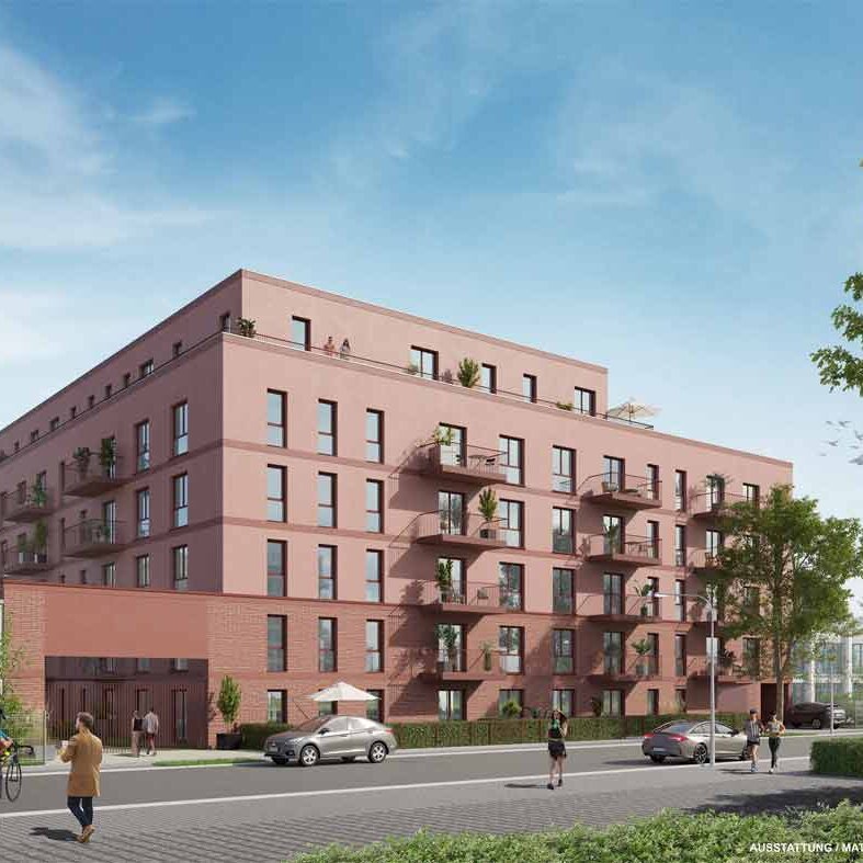 Straßenansicht des Mehrfamilienhauses mit roter Fassade, Staffelgeschoss und Balkonen. Vor dem Gebäude verlaufen Gehweg und Fahrbahn.