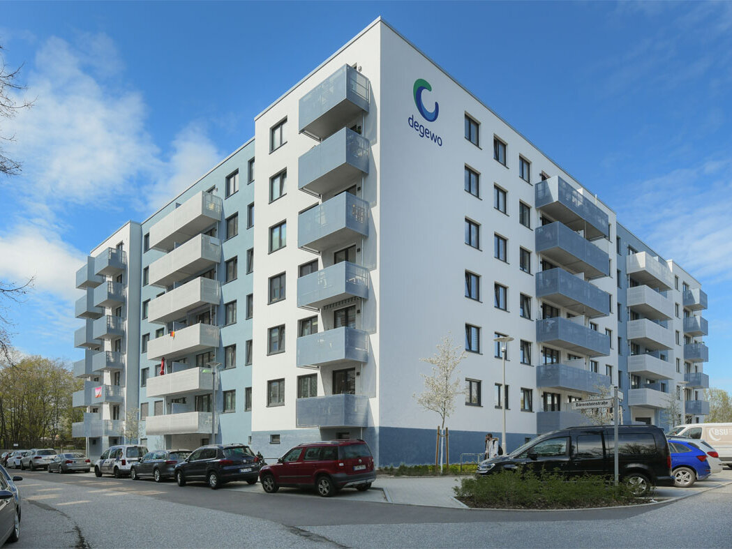 Außenansicht degewo-Neubau Pöhlbergstraße 9 Bärensteinstraße 5 mit parkenden Autos und degewo-Logo an Fassade.