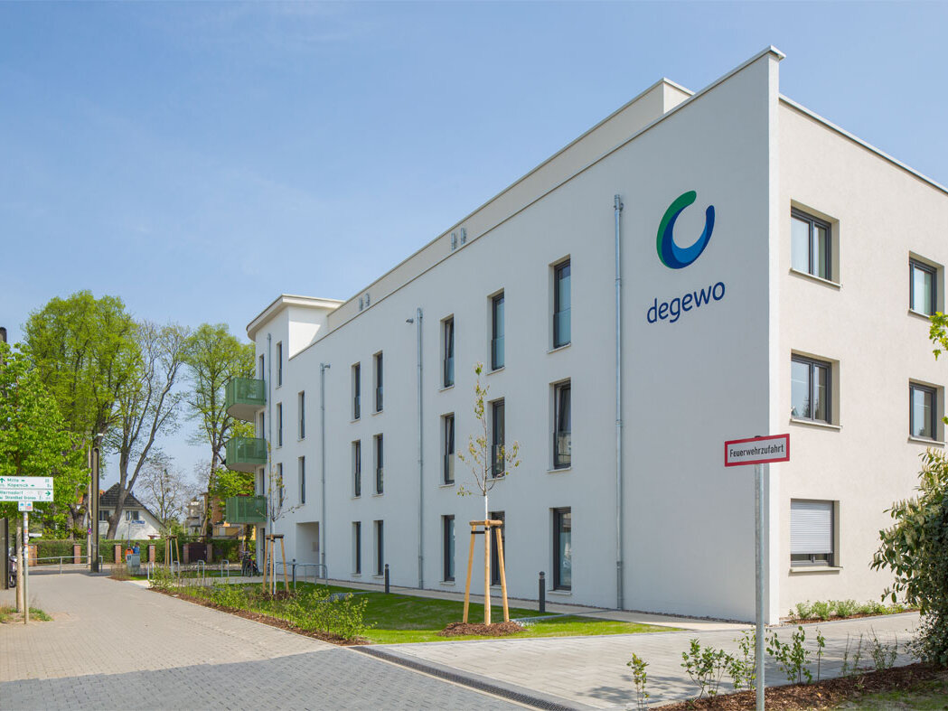 Straßenansicht degewo-Neubau Wassersportallee 13: Eckgebäude mit degewo-Logo an Fassade.