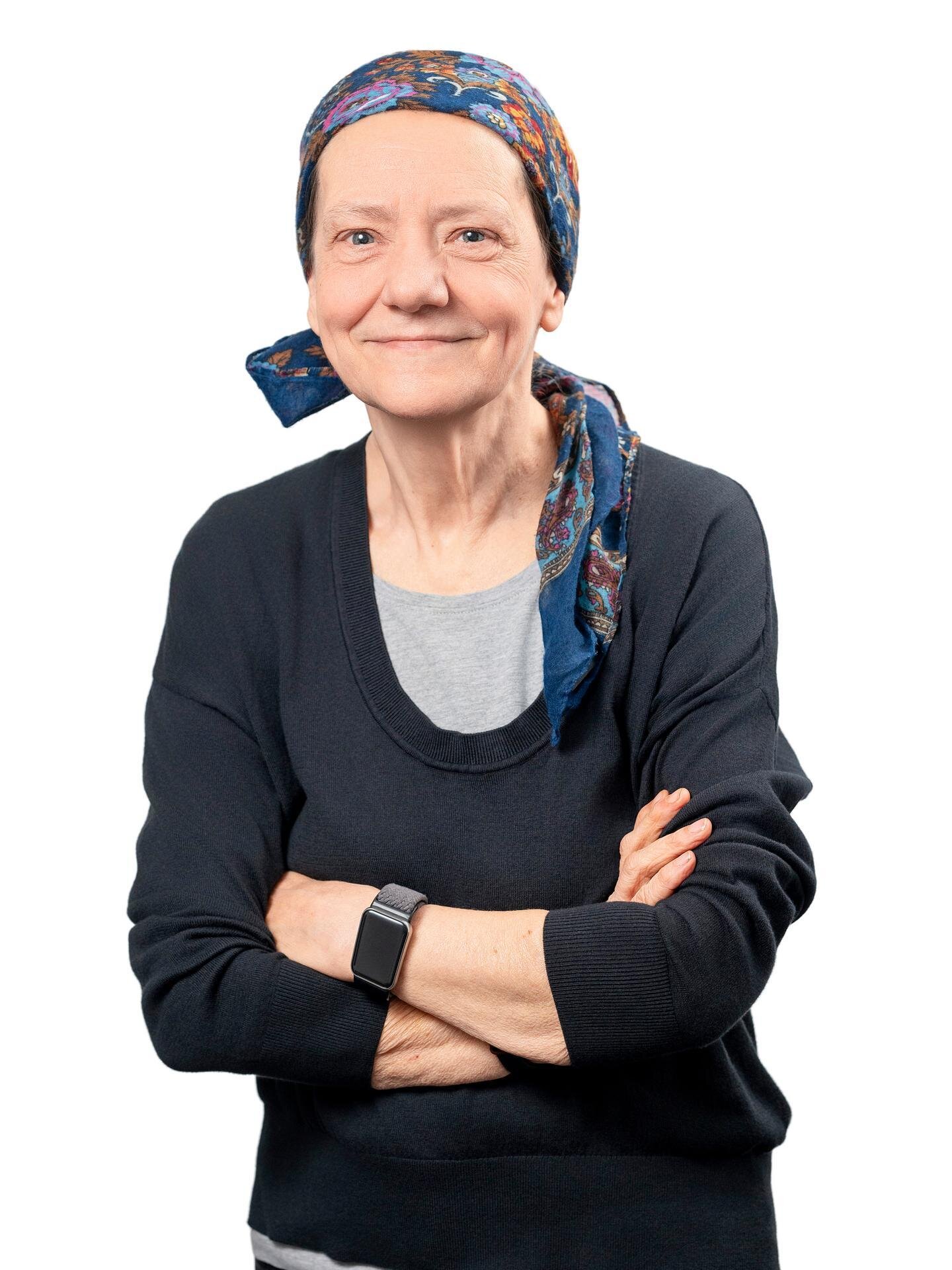 Portrait der Mieterbeirätin Dagmar Kresse. Sie trägt ein schwarzes Shirt und ein Haarband, hat die Arme vor der Brust verschränkt und lacht in die Kamera.