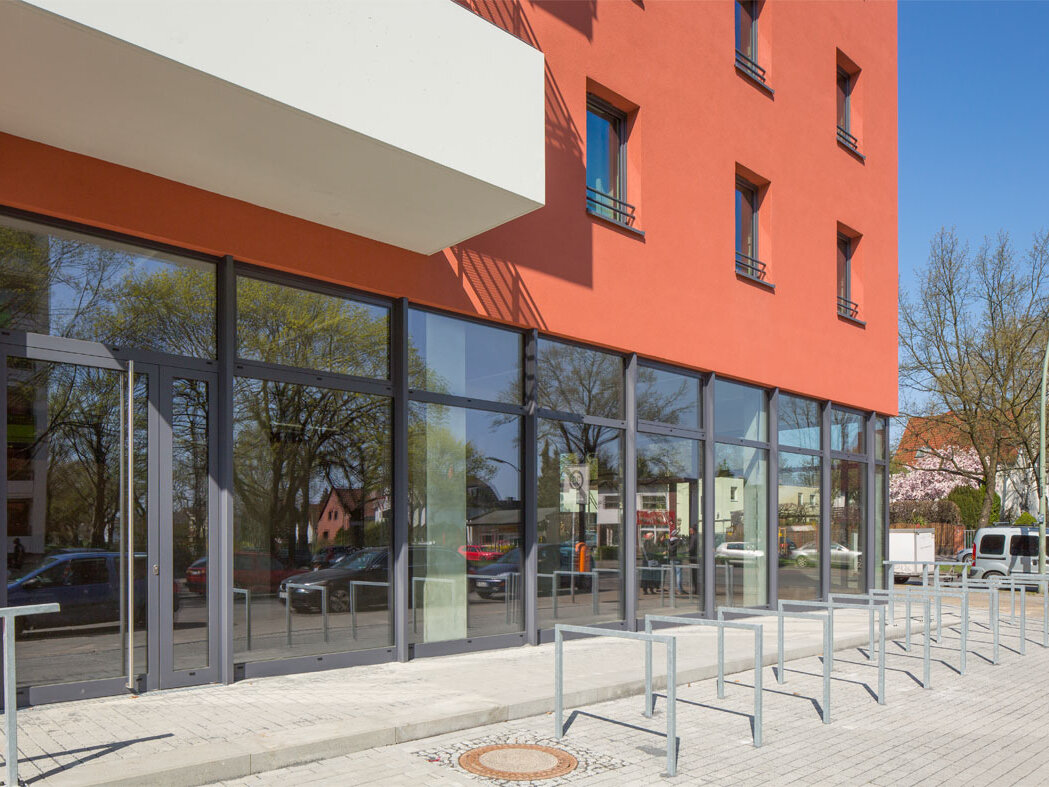 Außenansicht degewo-Neubau Käthe-Dorsch-Ring 23 mit Glasfront und Fahrradständern im Vordergrund.