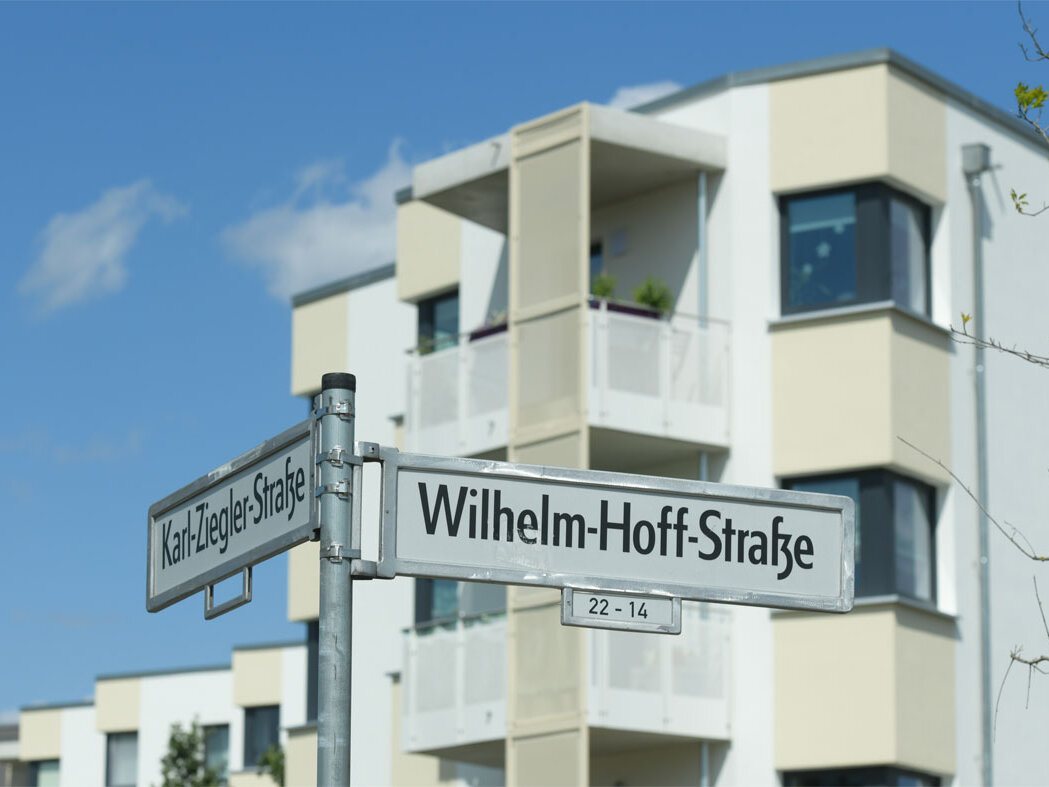 Außenansicht degewo-Neubau Wilhelm-Hoff-Straße 24 und 26: Eckgebäude mit Straßenschildern im Vordergrund.
