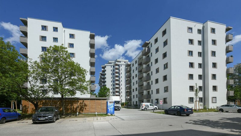 Außenansicht degewo-Neubau Theodor-Loos-Weg 15 und 15 A mit Parkplatz im Vordergrund.