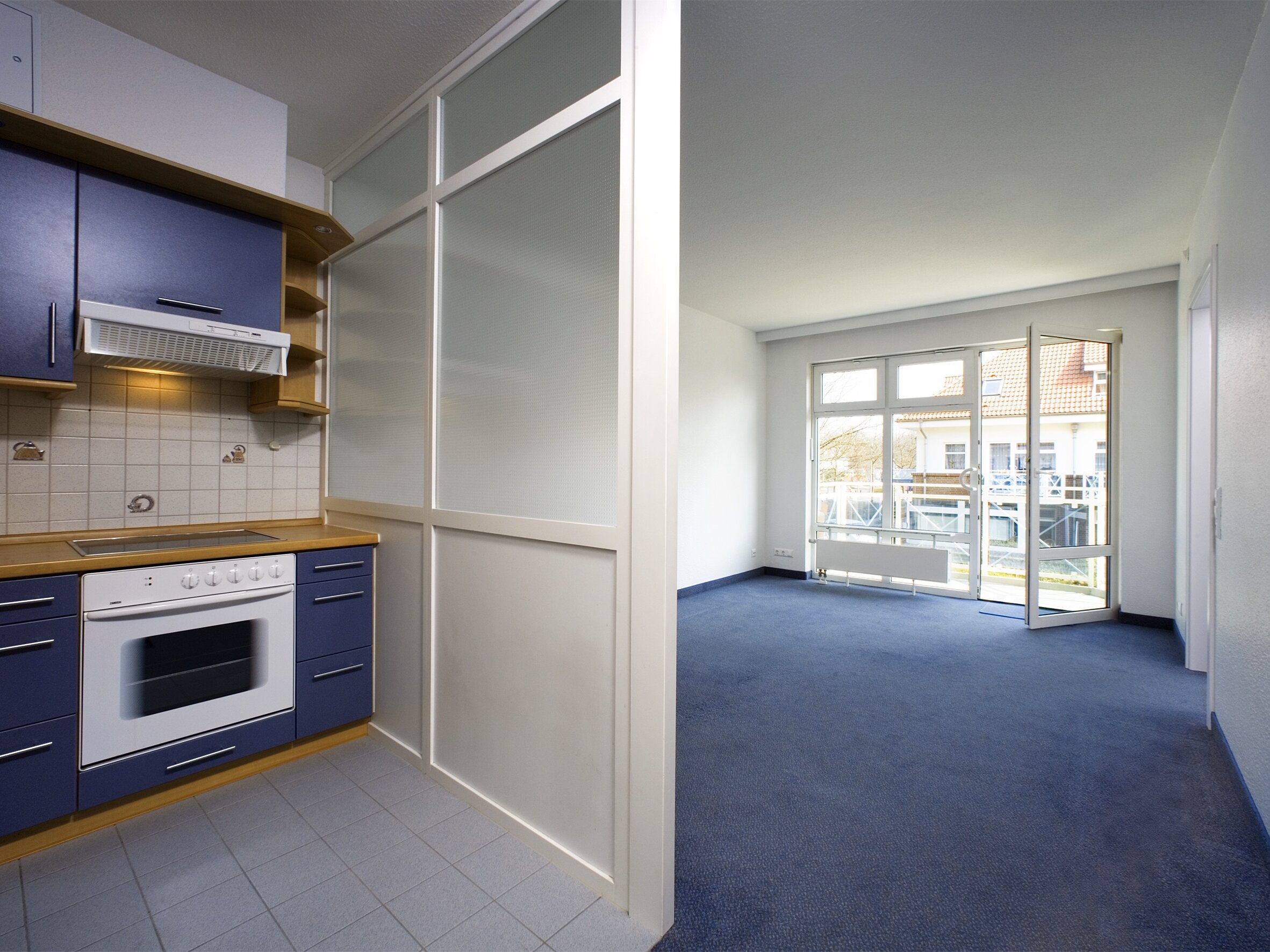 Blick auf Apartment mit blauem Teppich und kleinem Küchenbereich