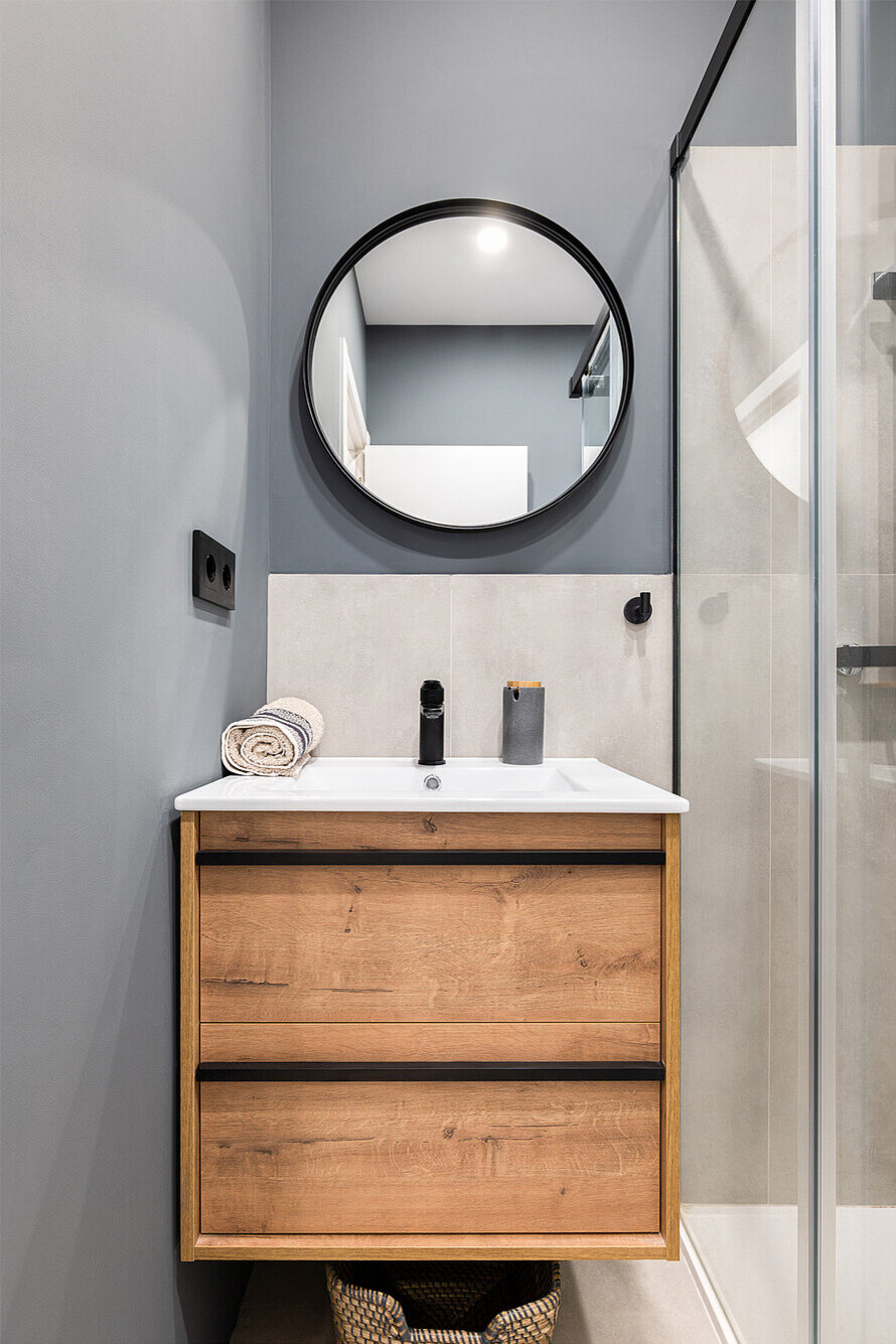 Blick ins kleine Badezimmer mit Waschbecken und Spiegel an der Wand