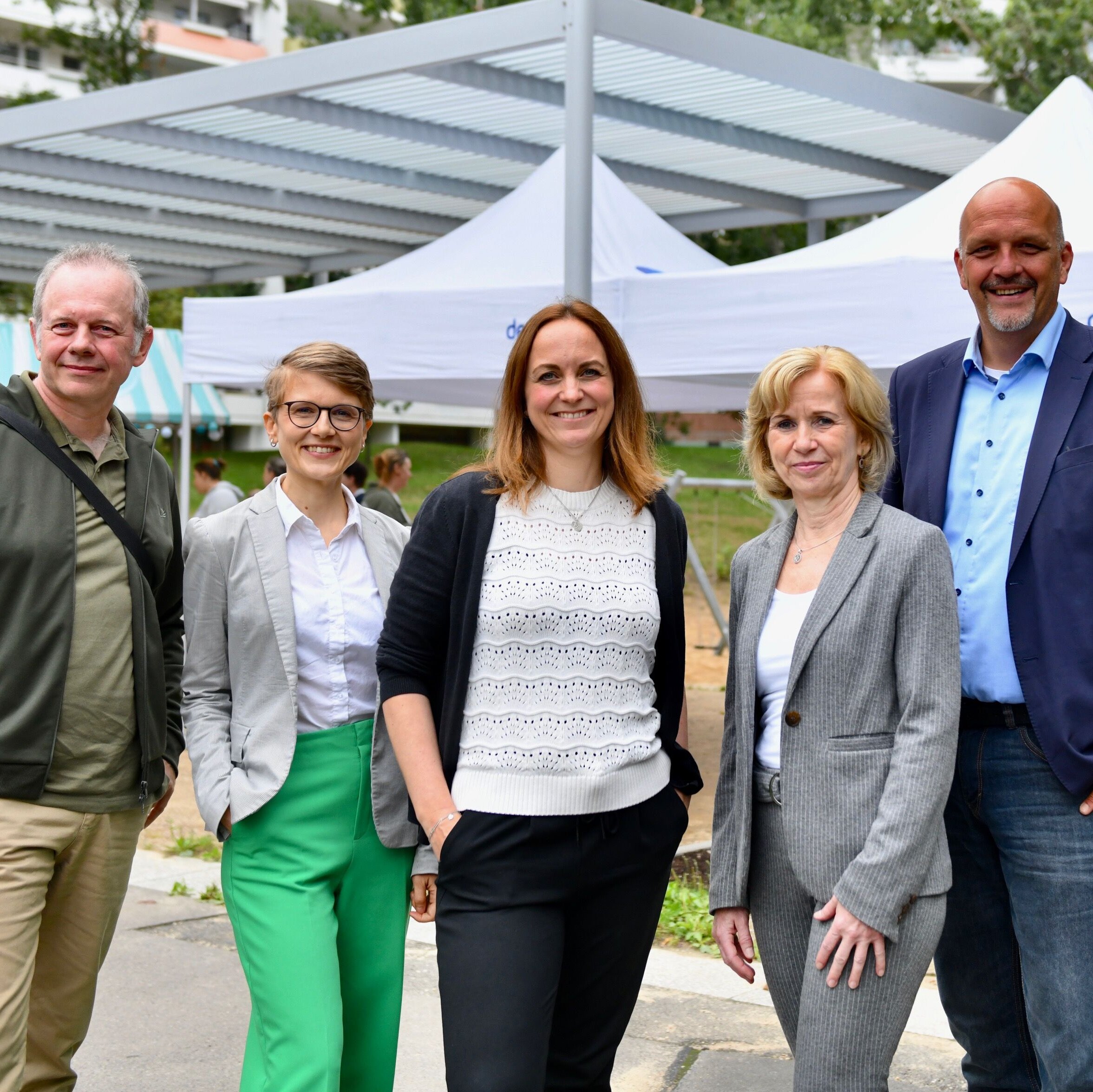 Fünf Personen stehen in einer Reihe nebeneinander.