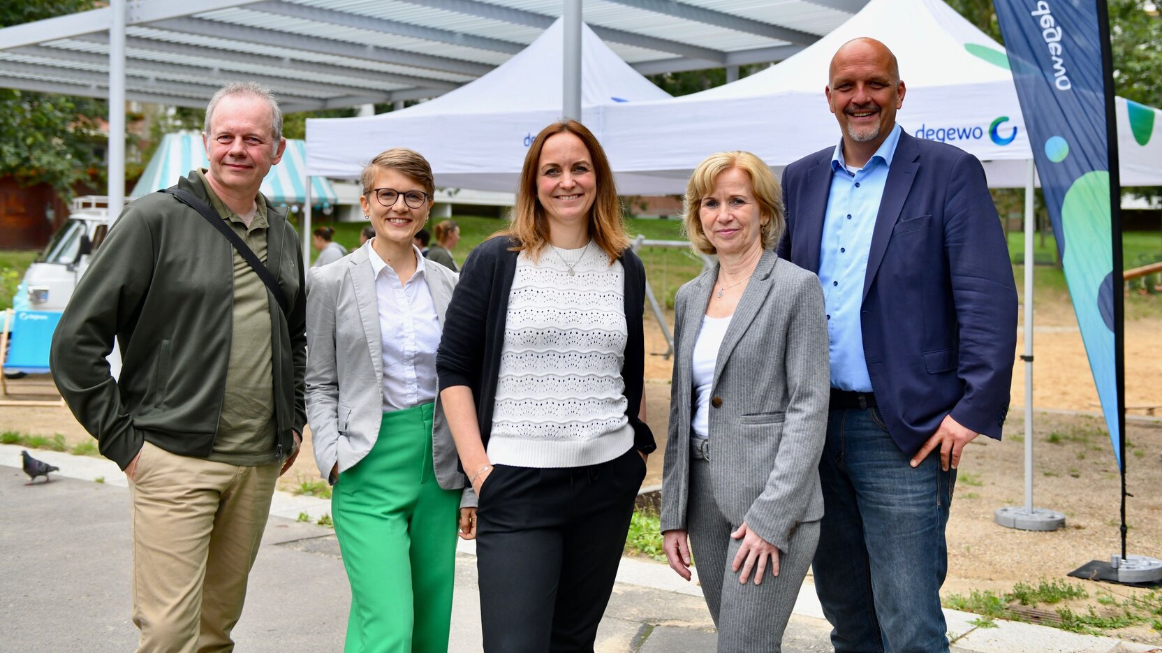 Fünf Personen stehen in einer Reihe nebeneinander.