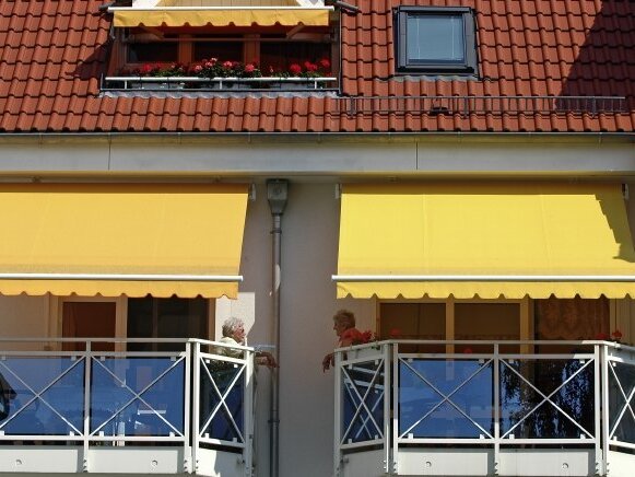 Blick auf zwei Balkone mit gelben Markisen