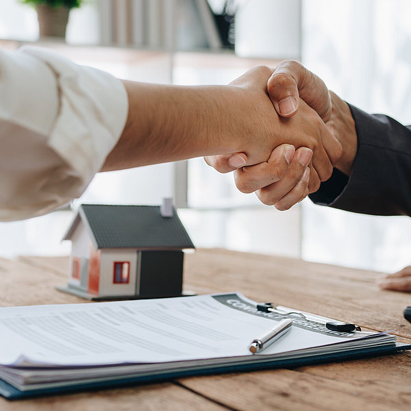 Hände begrüßen sich zu einem Gespräch am Konferenztisch