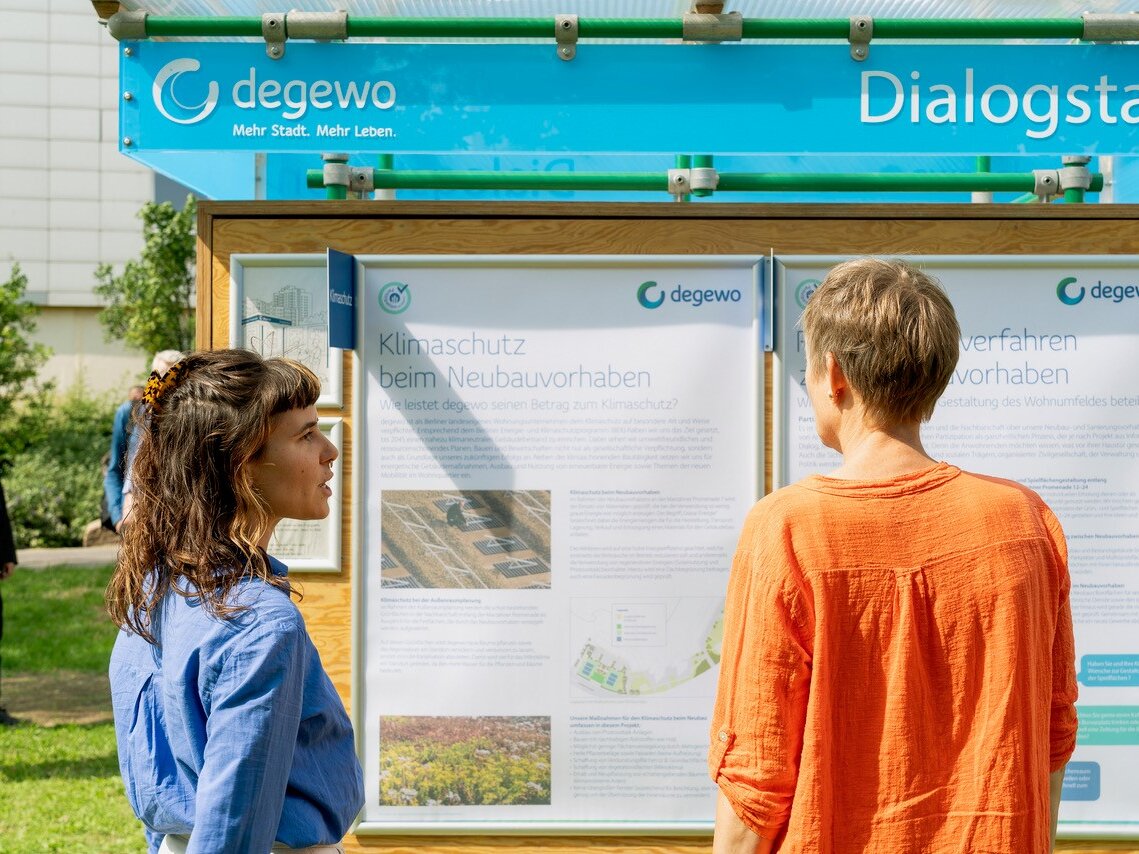 Zwei Frauen lesen Informationstafeln zum Thema Klimaschutz beim Neubauvorhaben an der degewo-Dialogstation.