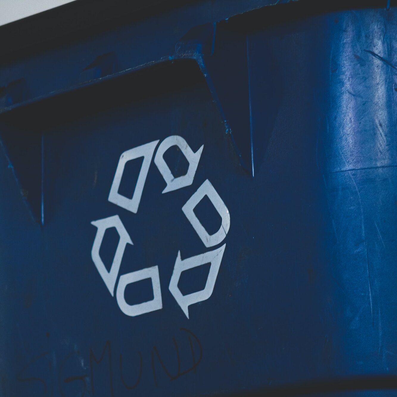 Eine blaue Mülltonne mit Recycling-Symbol auf der Vorderseite.