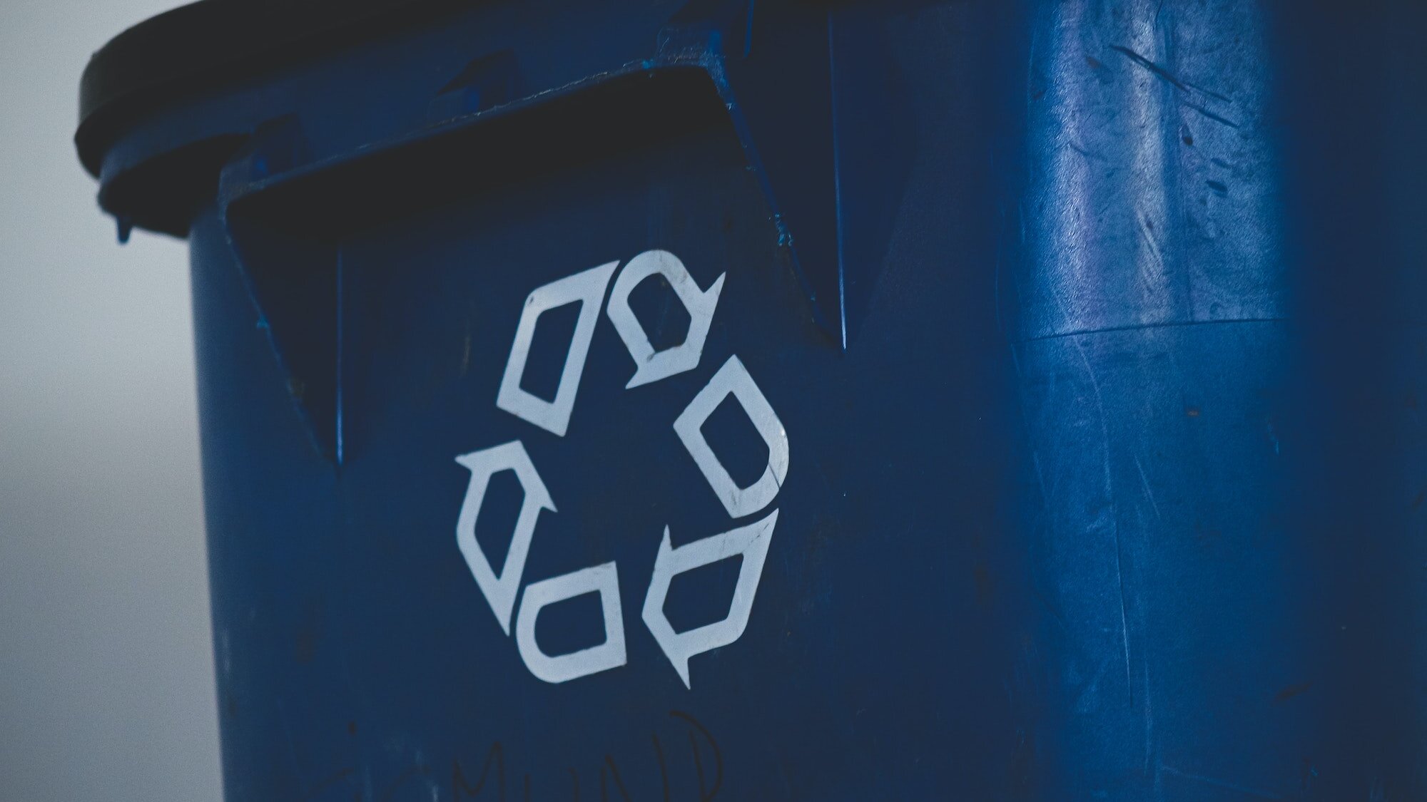 Eine blaue Mülltonne mit Recycling-Symbol auf der Vorderseite.