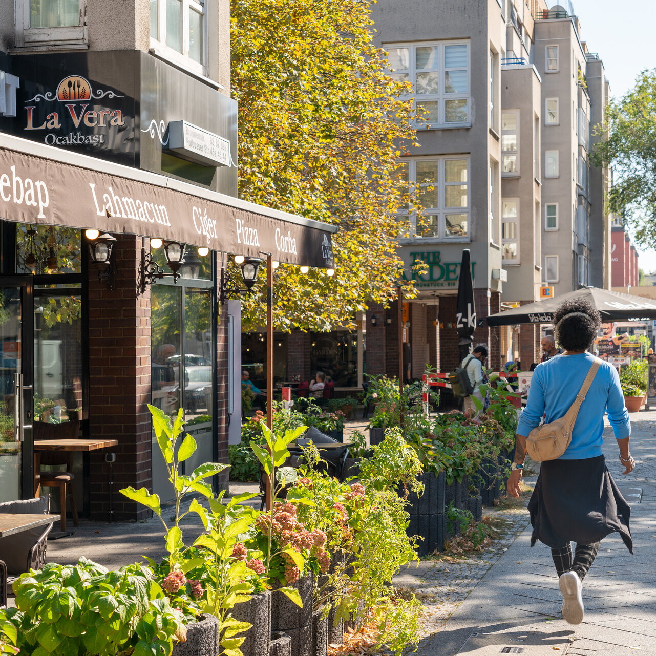 Geschäfte entlang der Brunnenstrasse im Somme. Eine Frau spaziert daran vorbei.