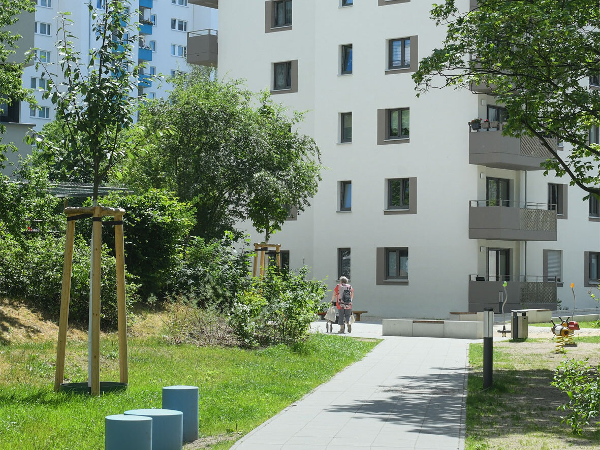 Außenansicht degewo-Neubau Theodor-Loos-Weg 15 und 15 A mit Weg im Vordergrund sowie links und rechts davon Grünfläche.