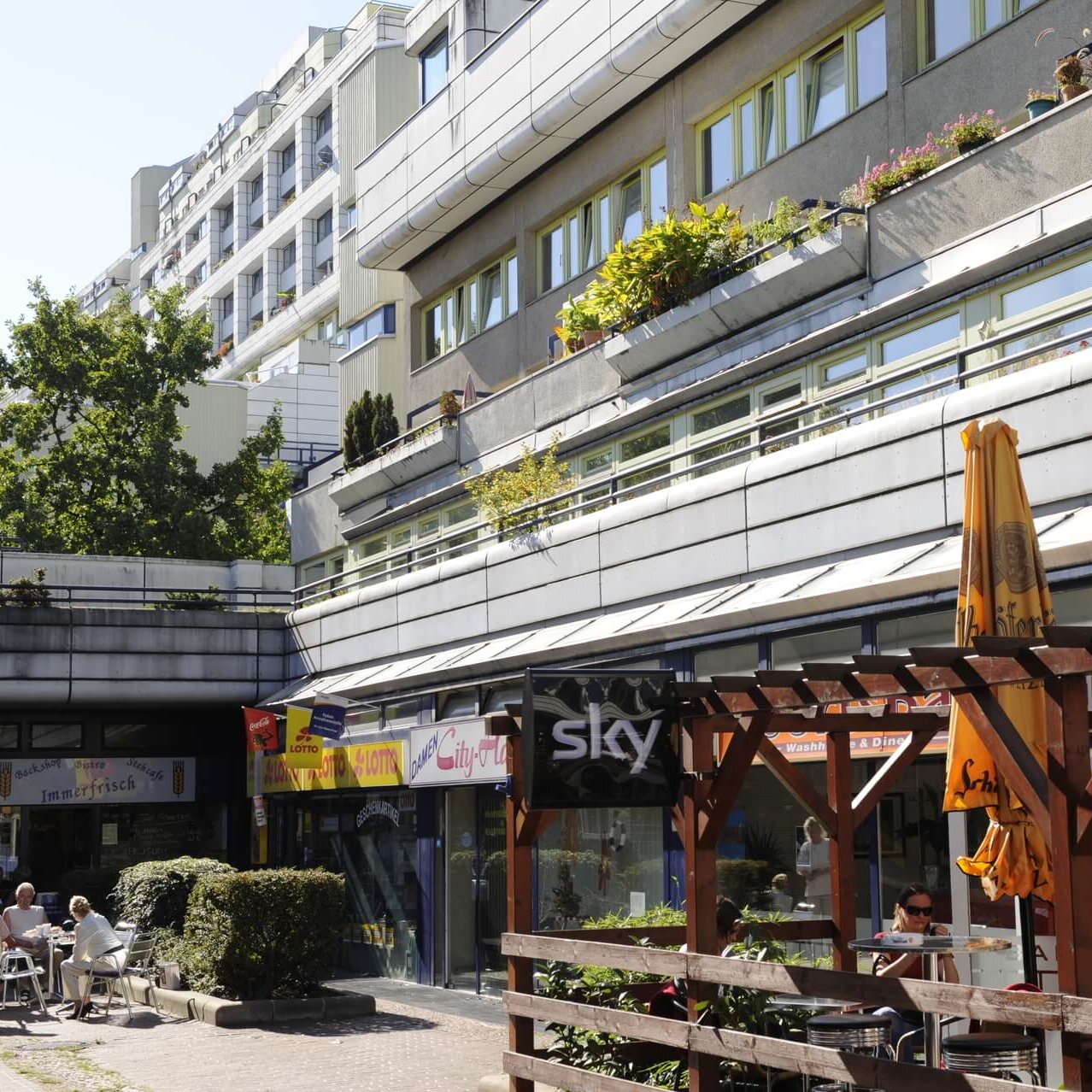 Geschäftszeile in einem Abschnitt der Schlangenbader Straße. Zu sehen sind ein Lotto-Geschäft, ein Restaurant und Wohnungen darüber.
