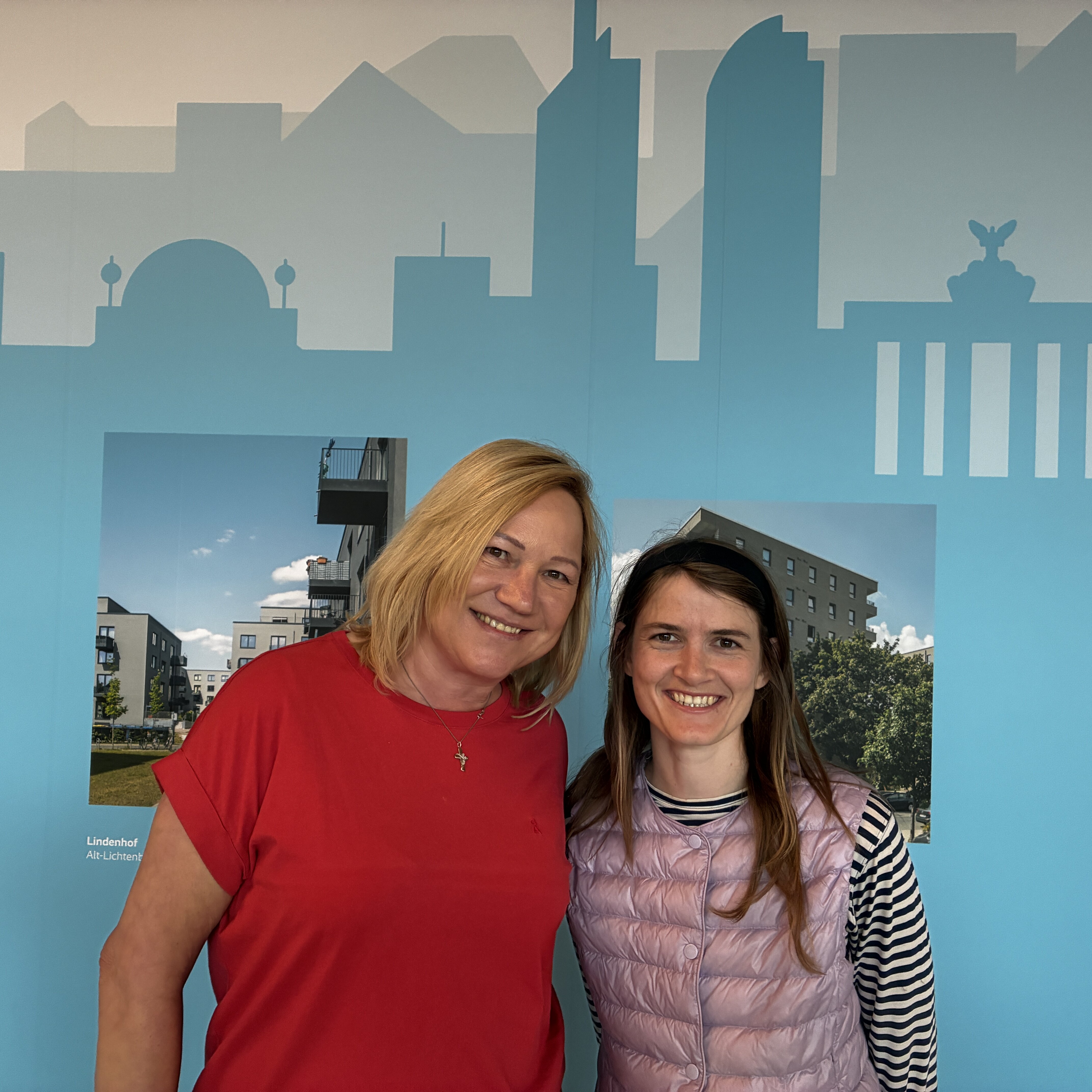 Claudia Märtner und Rebecca Geyer, Mietergremien-Koordinatorinnen bei degewo, stehen vor einer Wand mit Berlin-Kulisse und lächeln in die Kamera.