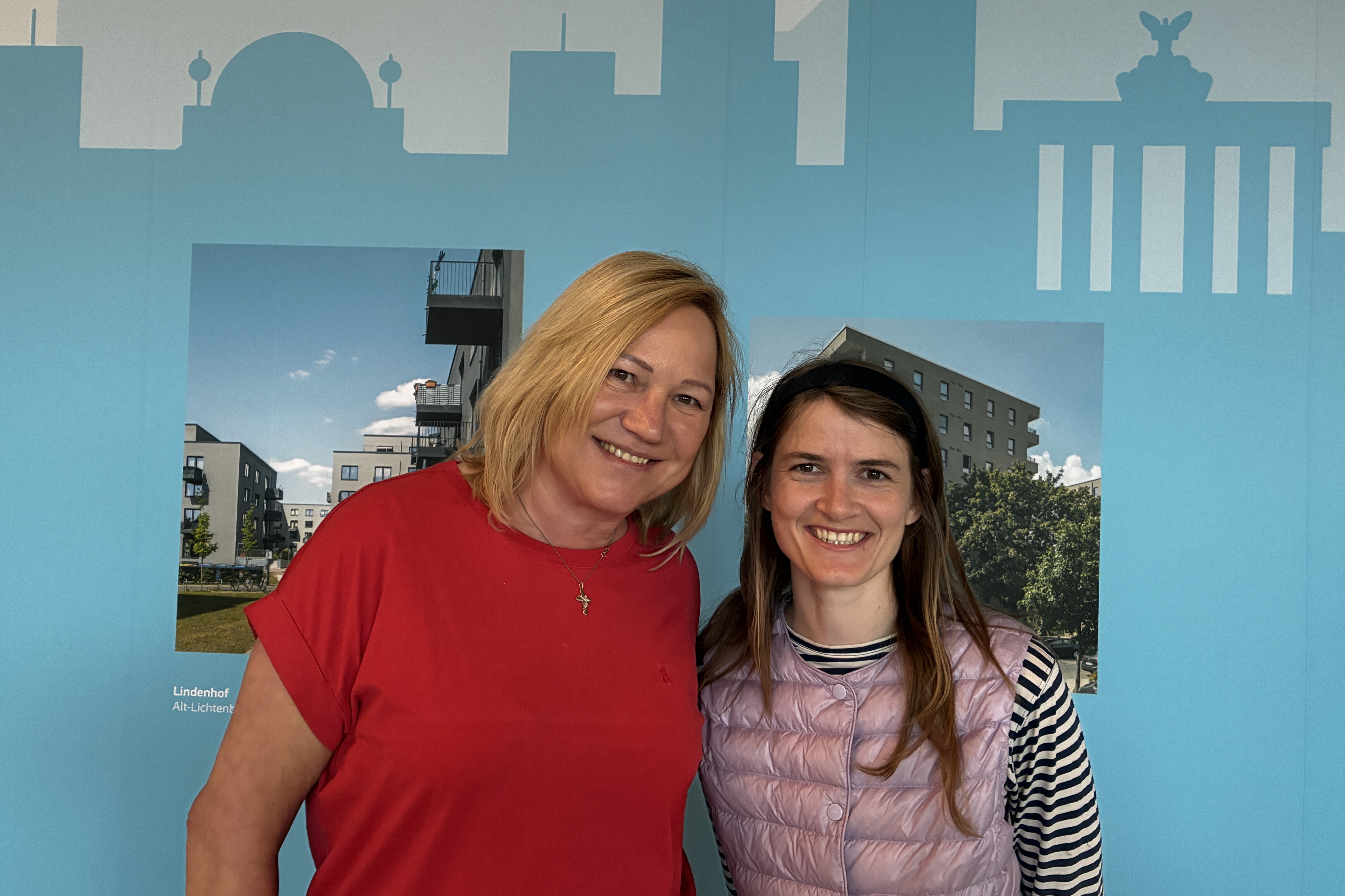 Claudia Märtner und Rebecca Geyer, Mietergremien-Koordinatorinnen bei degewo, stehen vor einer Wand mit Berlin-Kulisse und lächeln in die Kamera.