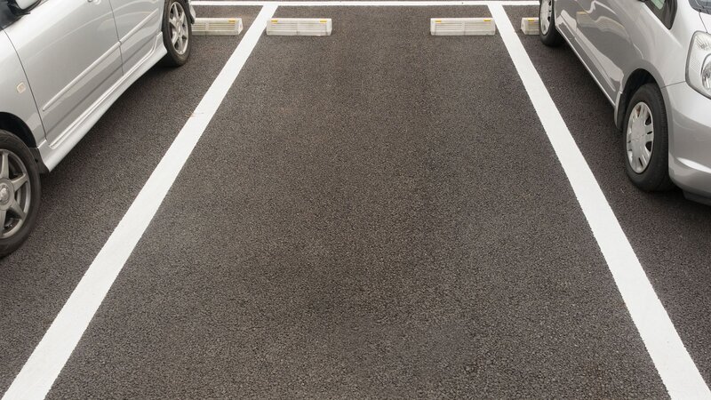 Neben einem freien Parkplatz ist links und rechts ein Auto geparkt.