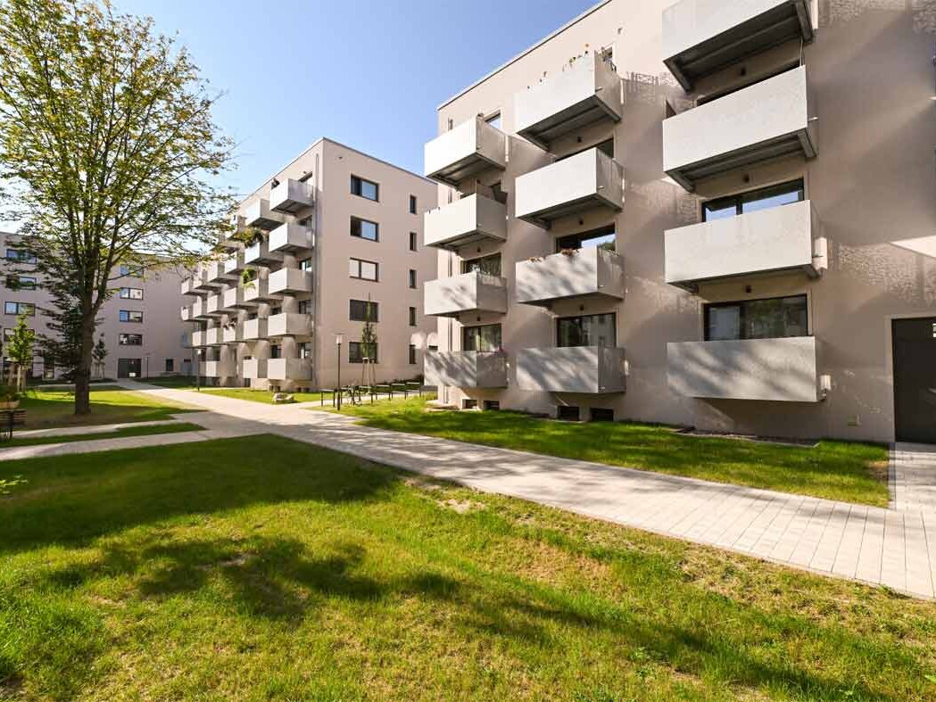 Außenansicht degewo-Neubau Malteserstraße 62: Rückseite mit Rasenfläche und Weg im Vordergrund.