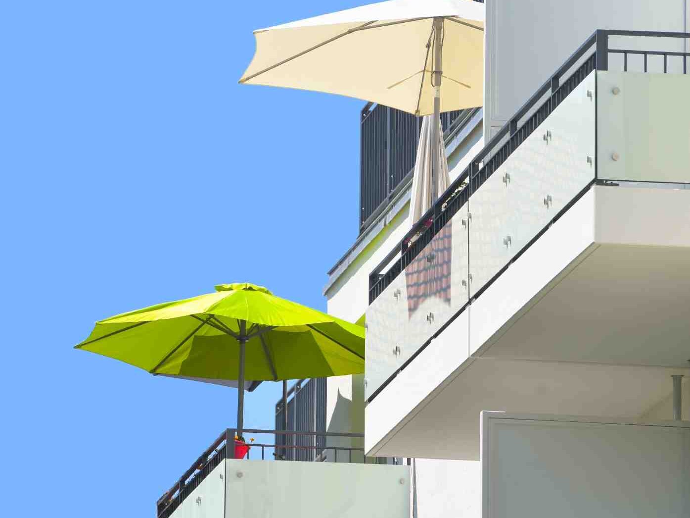 Außenansicht degewo-Ankauf Pepitahöfe: Fassade mit Balkonen, zwei davon mit Sonnenschirm.