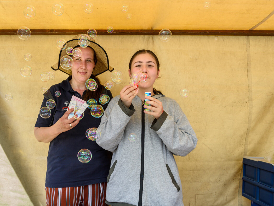 Zwei Frauen machen Seifenblasen in einem gelben Zelt
